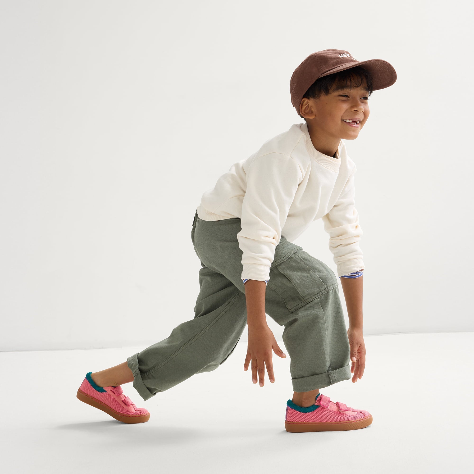 model | An alternate image of a child modeling The Kids Strap Sneaker in Watermelon. 