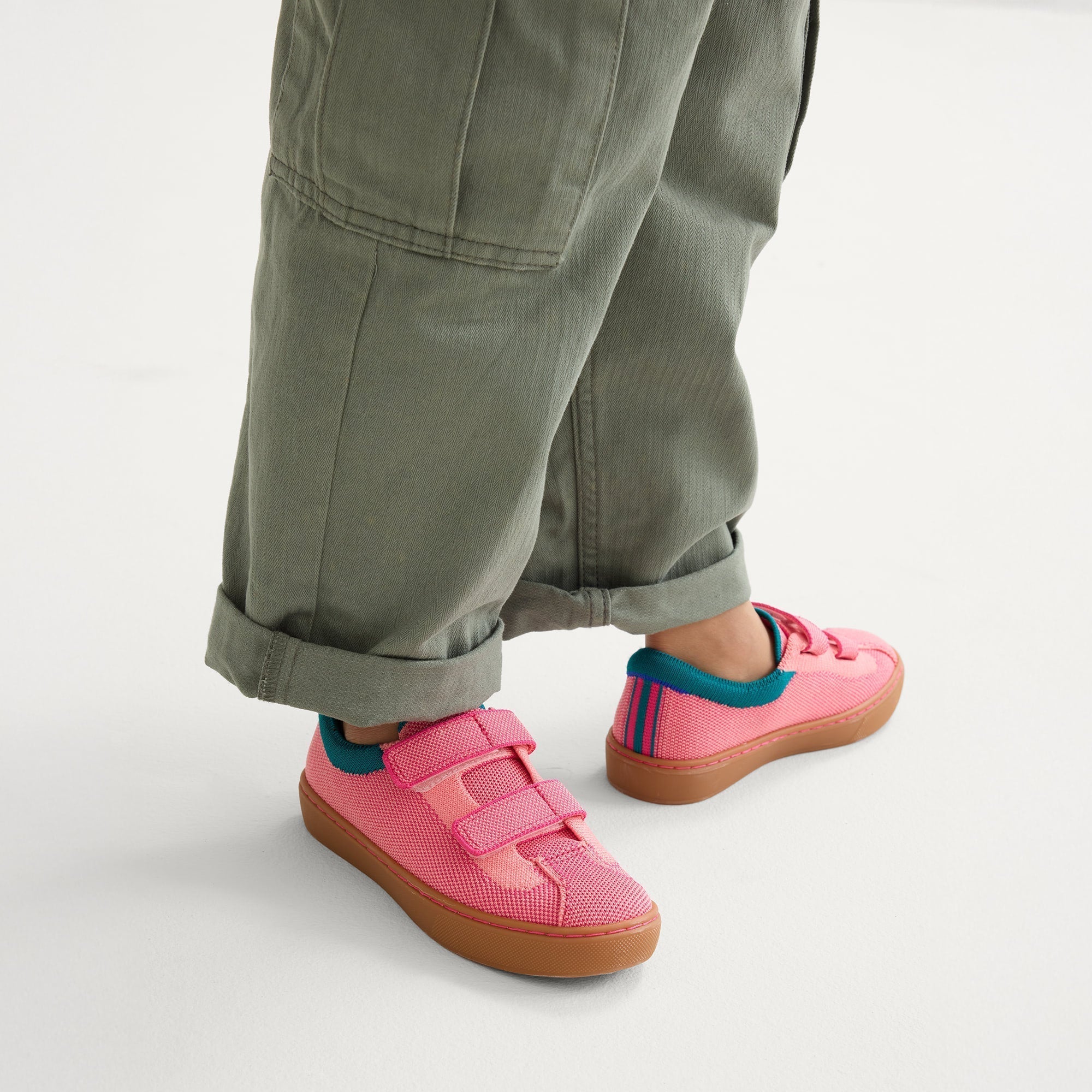 hover | A child modeling The Kids Strap Sneaker in Watermelon. 