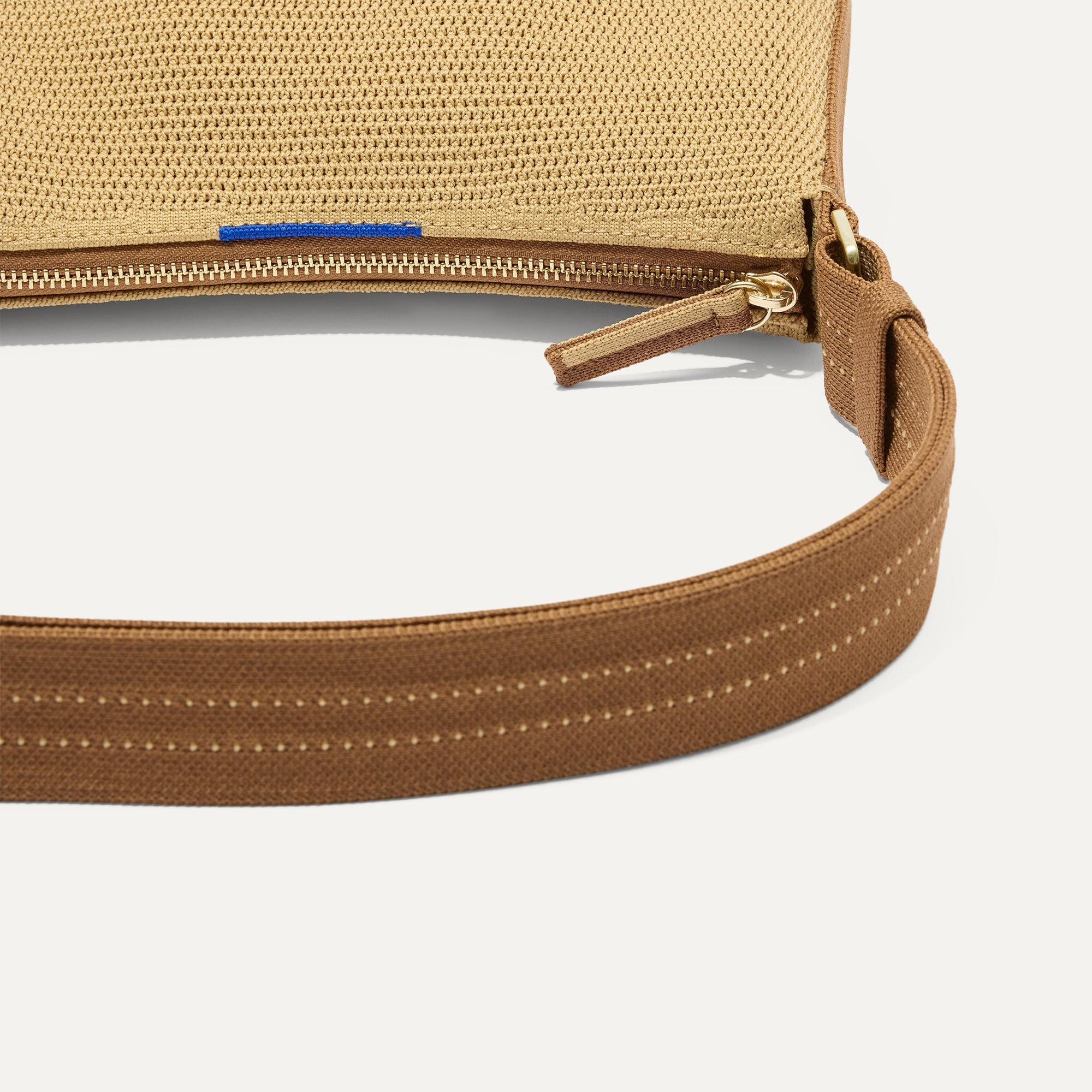 A closeup of The Casual Crossbody in Brown Butter Raffia-Knit, focusing on the crossbody strap. 