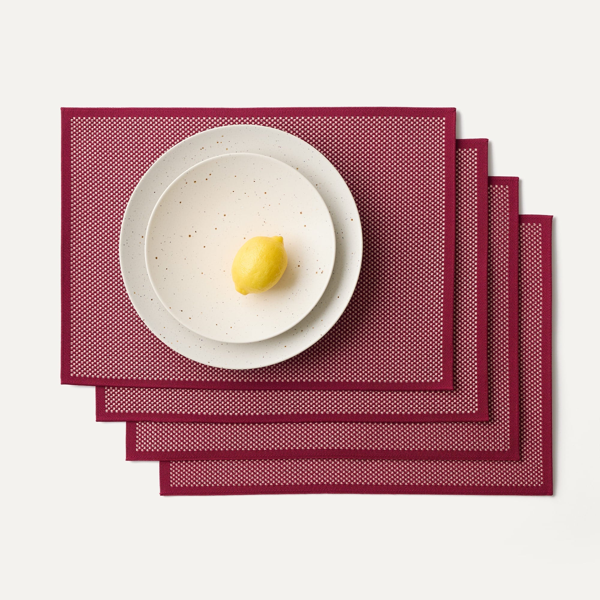 A set of four Placemats in Paprika shown with a plate setting.