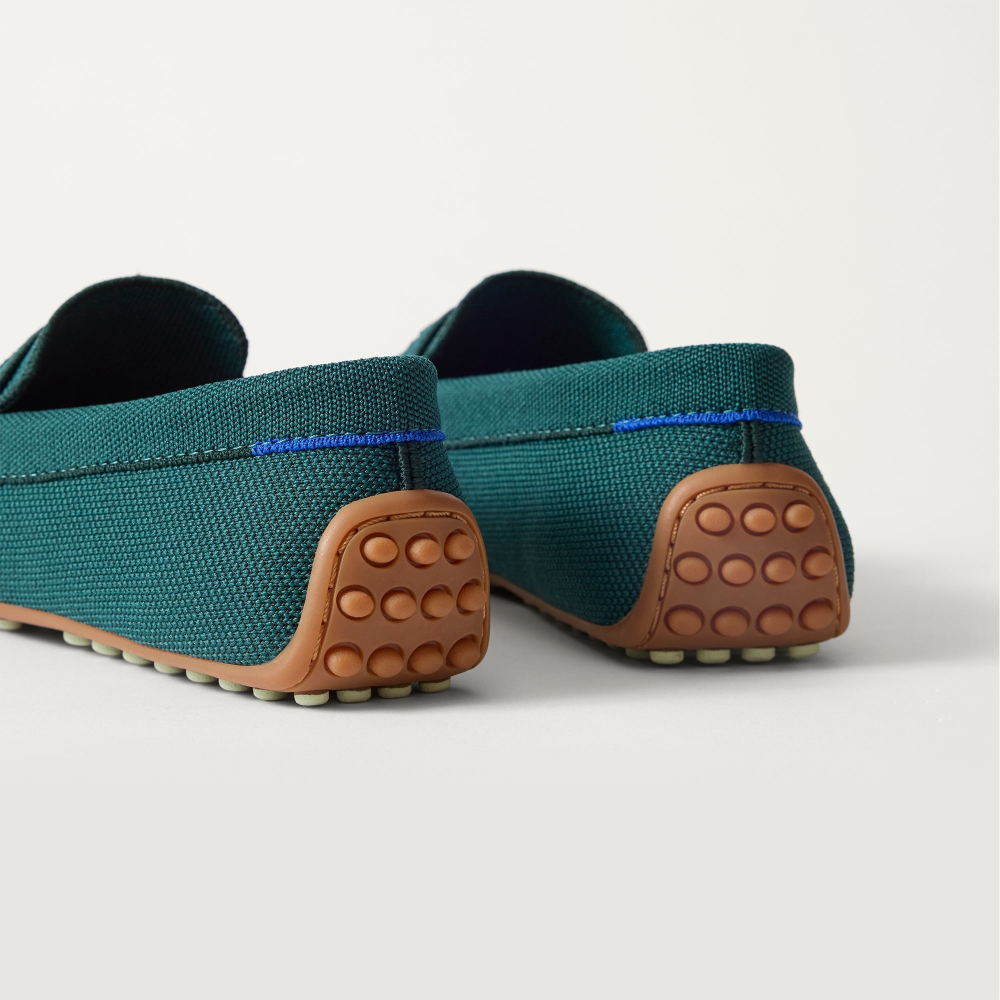 Close up of the heel of The Daily Driver in Deepwater, with raised peg outsoles and Rothy's signature blue halo. 