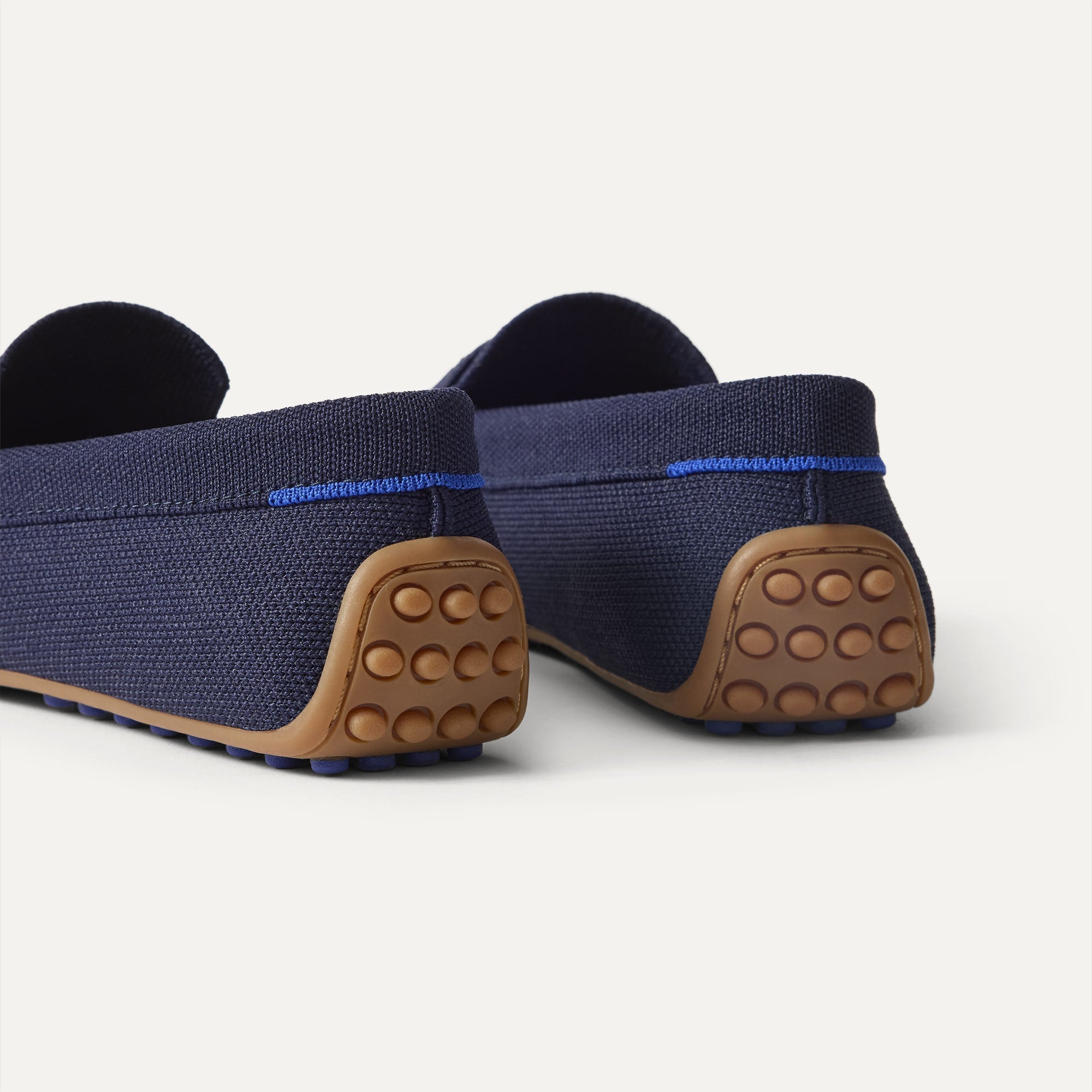Close up of the heel of The Daily Driver in Navy, with raised peg outsoles and Rothy's signature blue halo. 