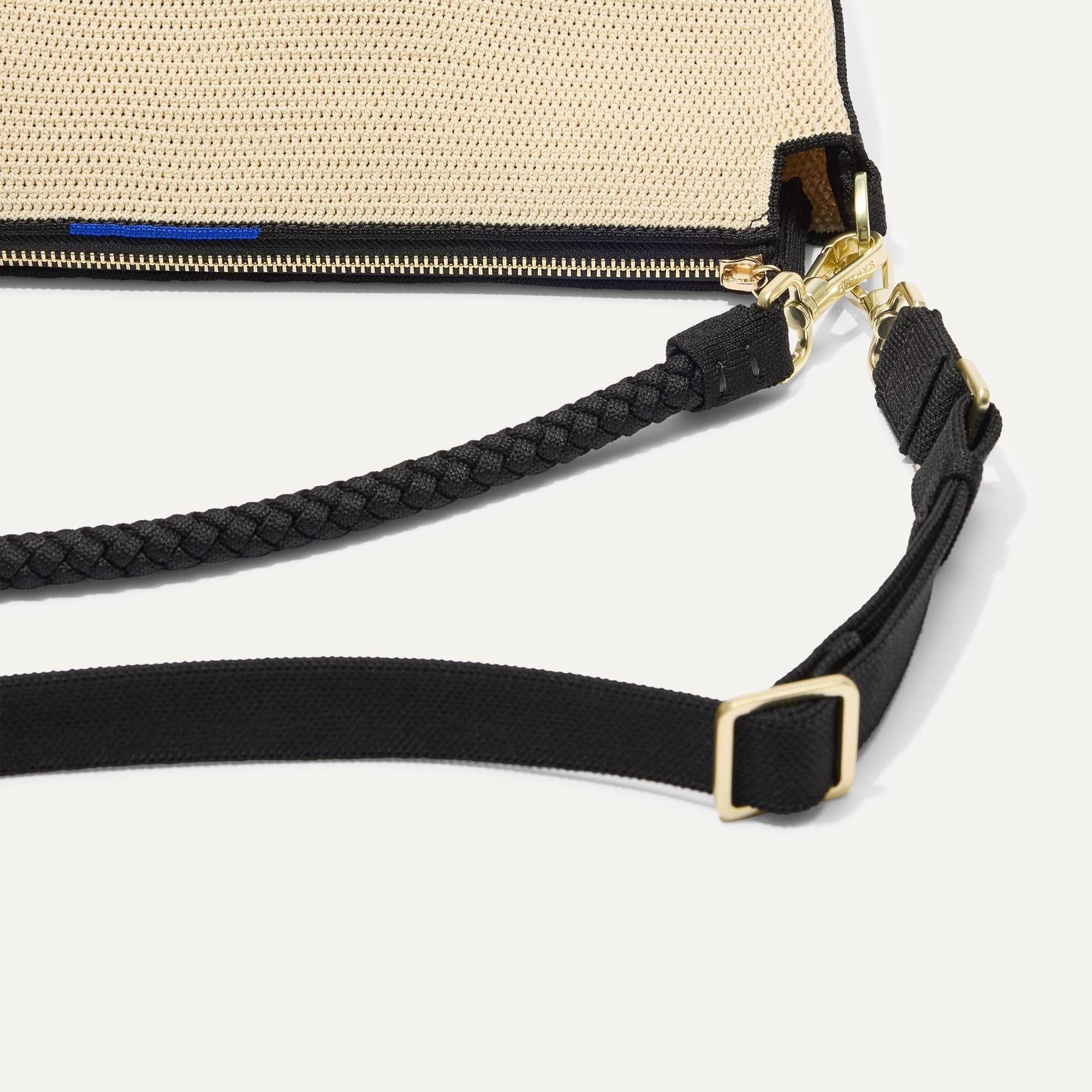 The Daily Crossbody in Black and White Raffia-Knit, lying flat, showing the detachable top handle and adjustable crossbody strap.
