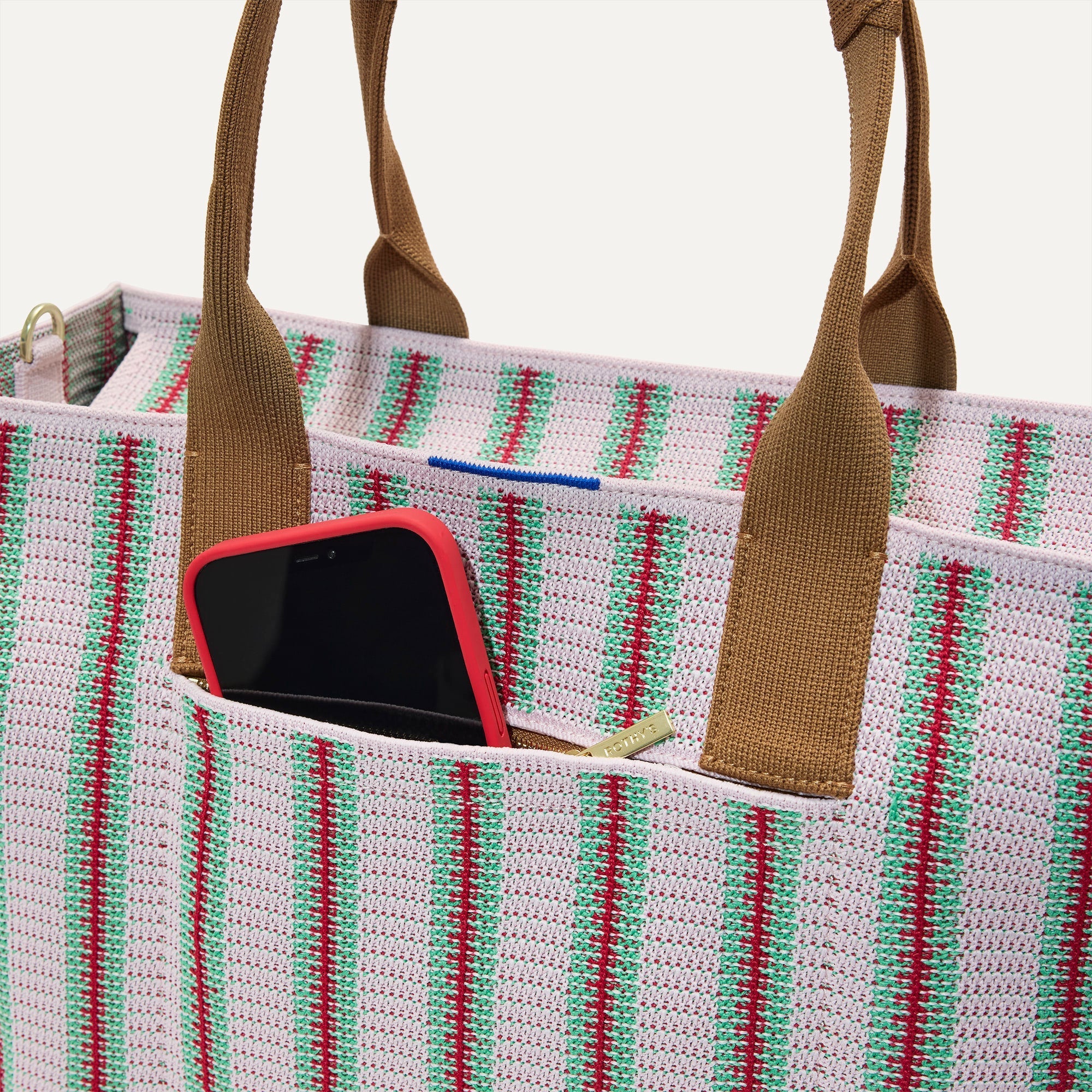 A closeup of The Classic Tote in Watermelon Market Stripe, focusing on the exterior zip pocket. 